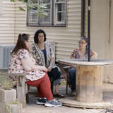 Adult woman sits outside with her mother and aunt who provided kinship care