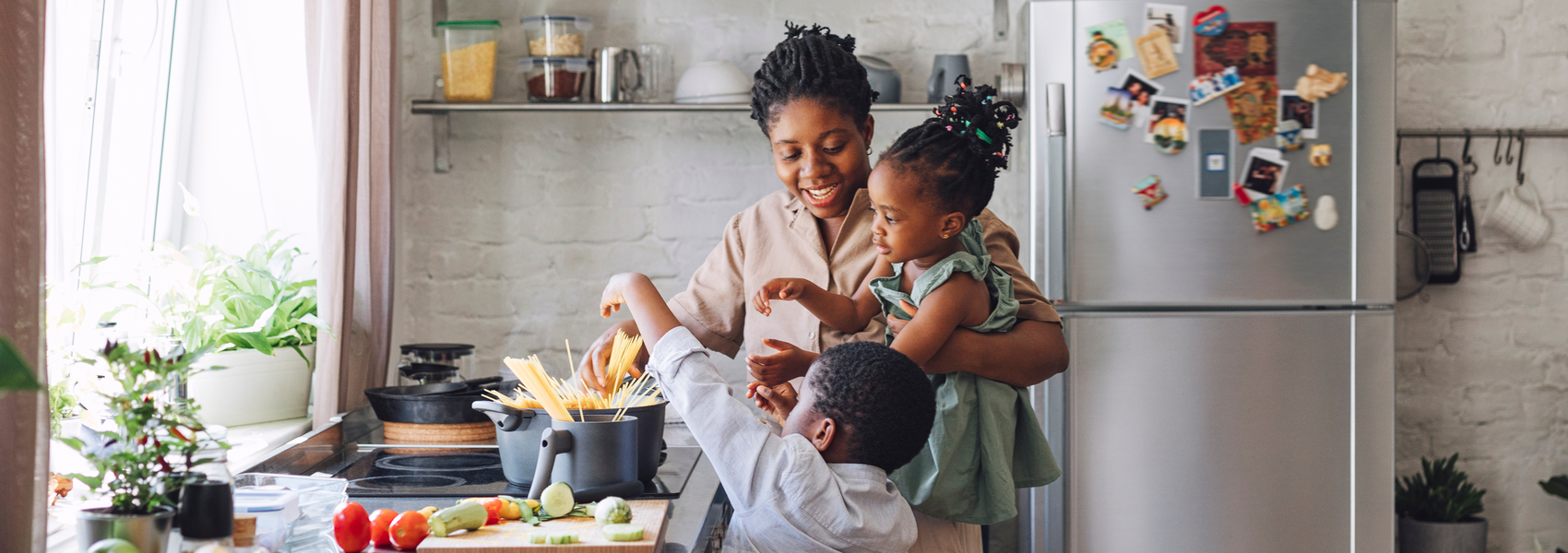 Black foster mother involves children in cooking pasta 