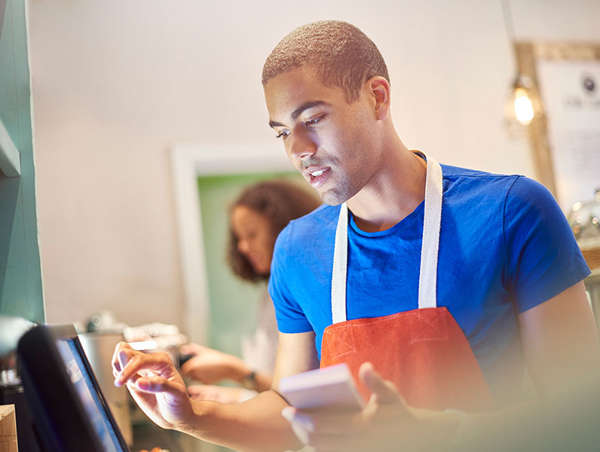 african american teenager enters an order into the cash register at rising grinds cafe