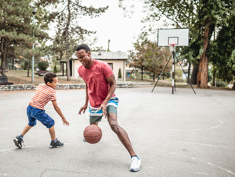 adult mentor plays basketball with young adoptee