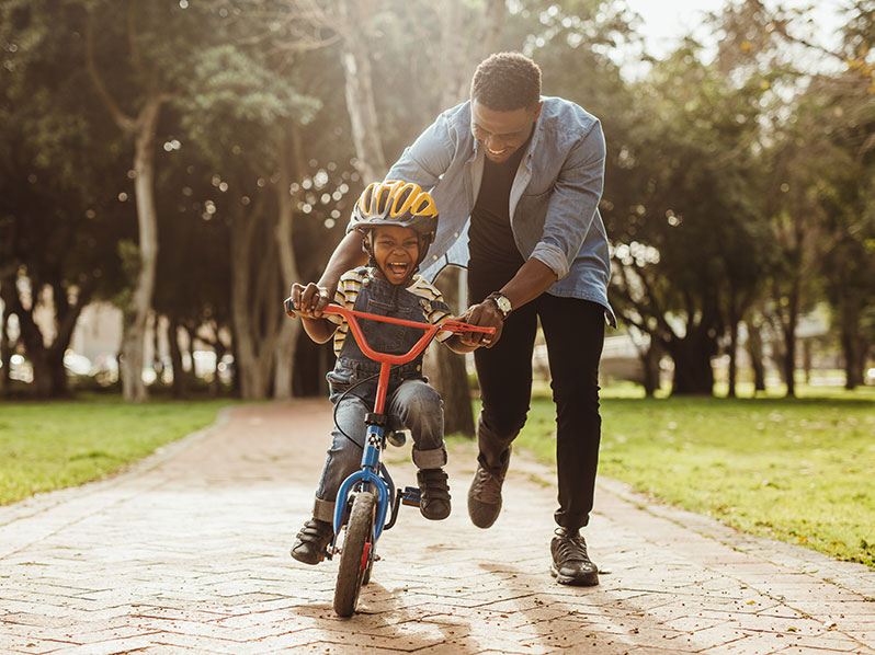 adoptive dad helps his son learn to ride a bike