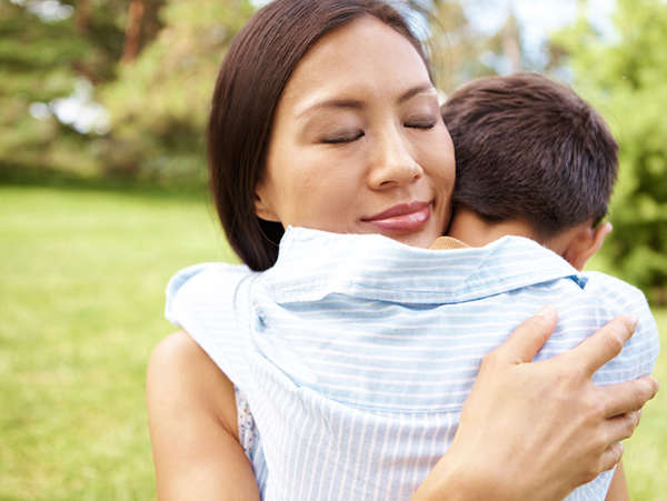 asian mother hugs her son outside in their backyard