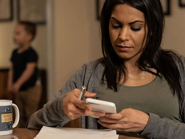 pregnant woman researches cheap counseling options while her son plays