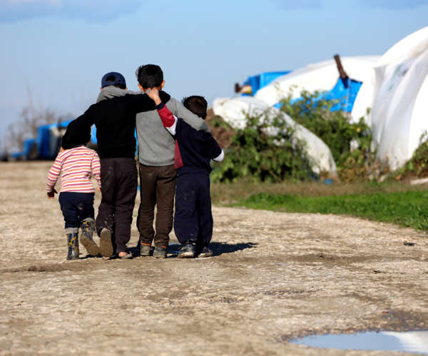 Group of refugee children walk through refugee camp