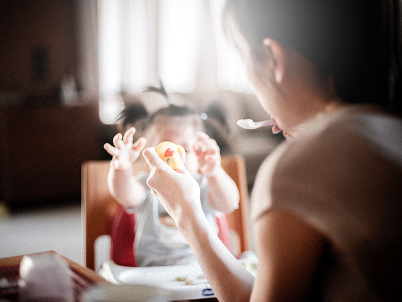 young mother feeds her hungry toddler