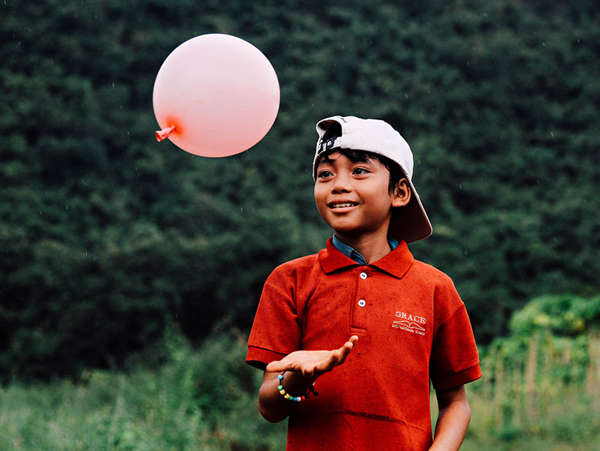 young adopted boy plays with a balloon in his backyard