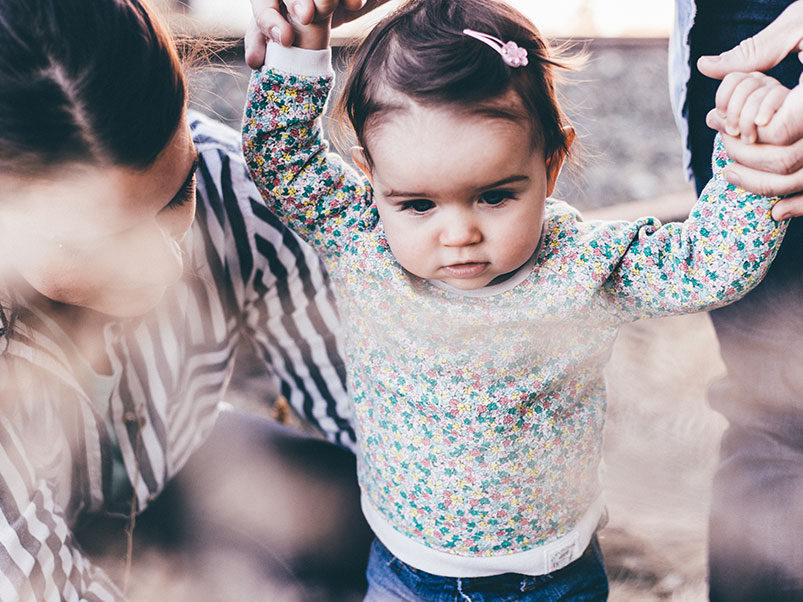 little girl holds the hands of her adoptive mom and birth mom