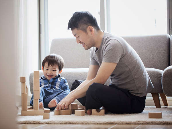Asian man plays with blocks with the boy he's caring for through safe families