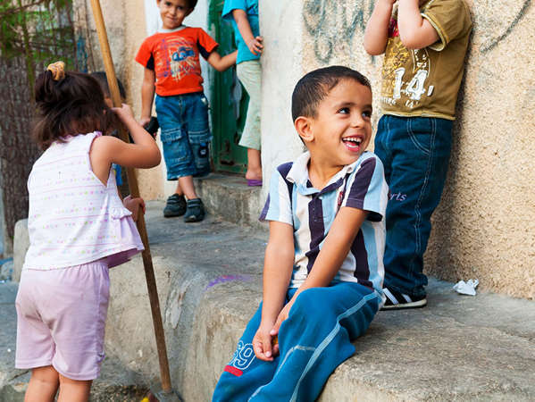 young refugee boy smiles while sitting on a step with his friends