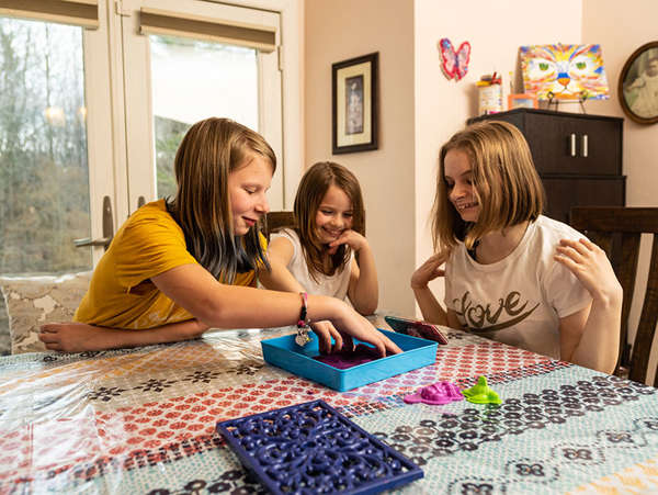 three girls in foster care play games at the kitchen table