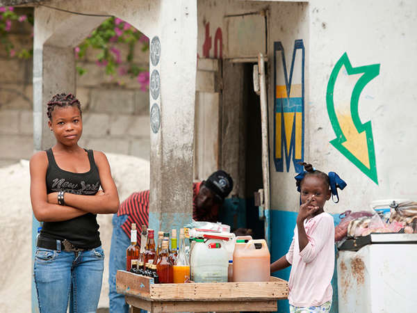 A Haitian mother sells drinks at her market stand with her young daughter