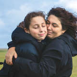 A mom embraces her teen daughter  