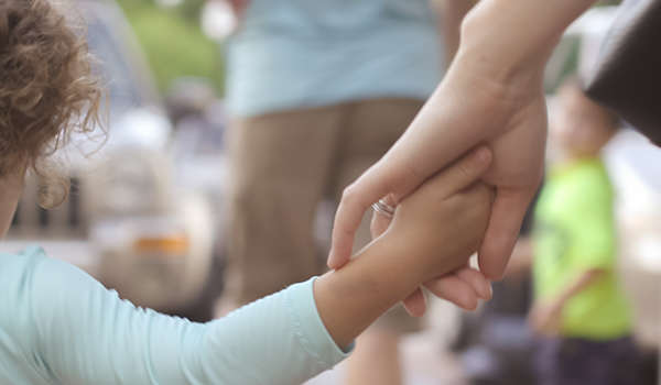 adoptive mother holds the hand of her young child