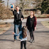 White male foster parent tosses beach ball to migrant girl