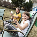 two girls roast marshmallows over a fire in the backyard of their adoptive parents' house