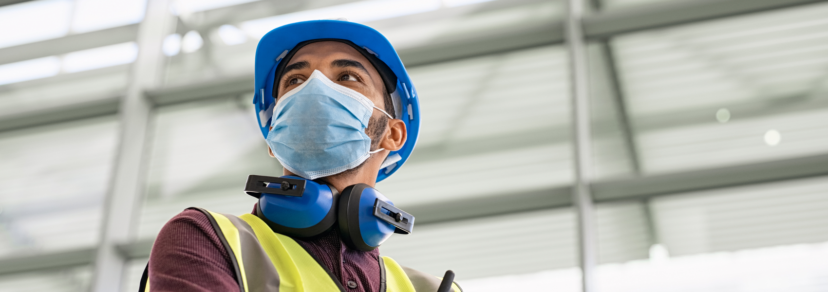 Afghan engineer with hard hat and hearing projection, wearing a mask 