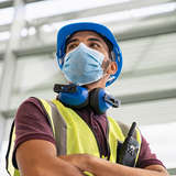 Afghan engineer with hard hat and hearing projection, wearing a mask 