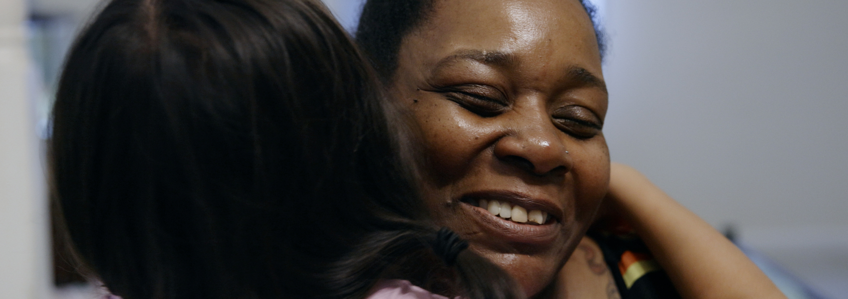 Black foster mother hugs a refugee teenager