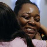 Black foster mother hugs a refugee teenager