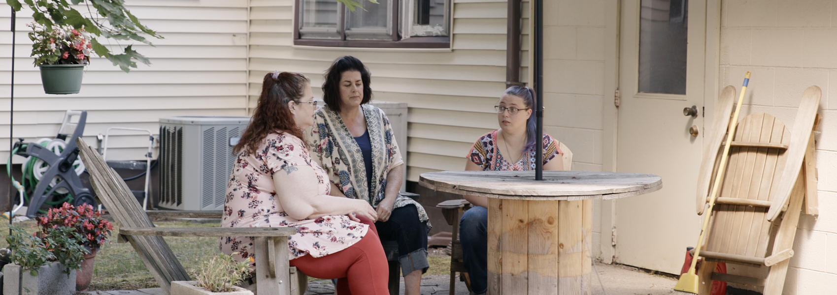 Adult woman sits outside with her mother and aunt who provided kinship care