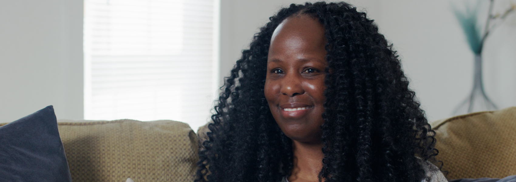 Black woman landlord smiles on couch