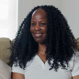 Black woman landlord smiles on couch