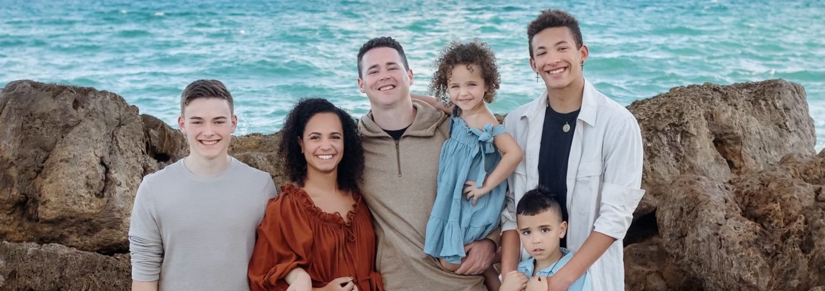 diverse family with teenagers adopted from foster care pose at beach