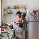 Black foster mother involves children in cooking pasta 