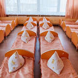 identical, small orange beds fill a room at an orphanage