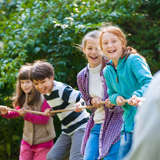 Diverse kids play tug-of-war outside