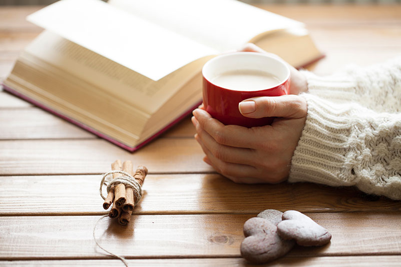 adoptive mother holds a coffee cup as she reads a book