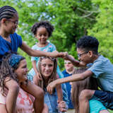 diverse foster kids climb on shoulders of older kids