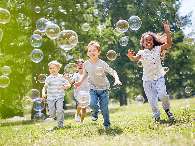 diverse group of children blow bubbles in the yard