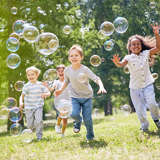 diverse group of children blow bubbles in the yard