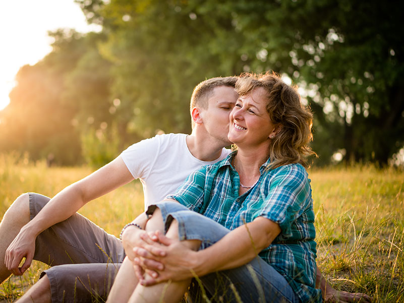adopted son kisses his birth mother on the cheek in a sunny field