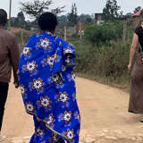 A group of adult refugees travels along a dirt road.