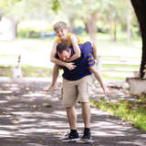 young white male climbs on his birth father's back outside