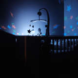 a crib is lit up showing a mobile in the nursery